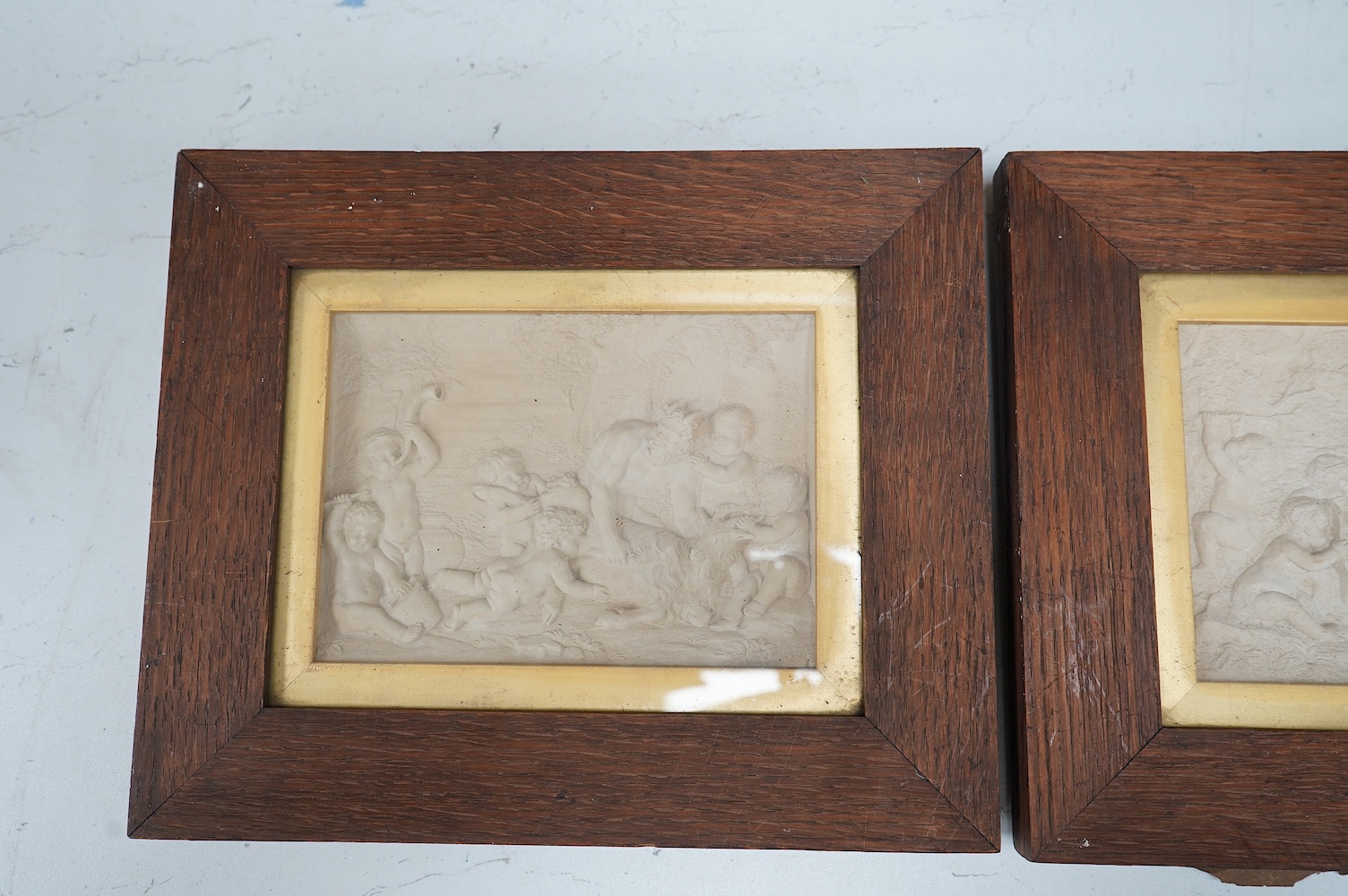 Three plaster relief panels depicting putti, framed, 21 x 25cm. Condition - two fair, one damaged